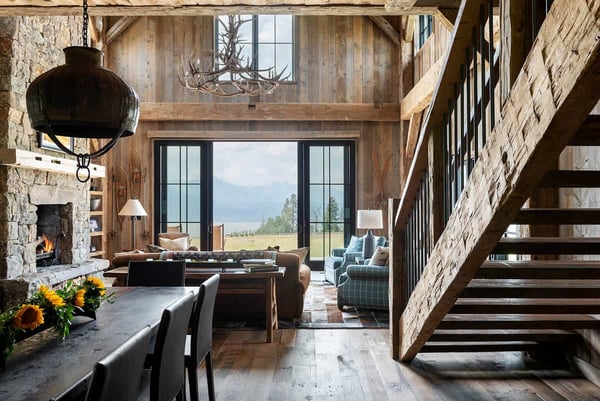 Interior staircase in a rustic farmhouse barndominium living room leading out to a beautiful country scene.
