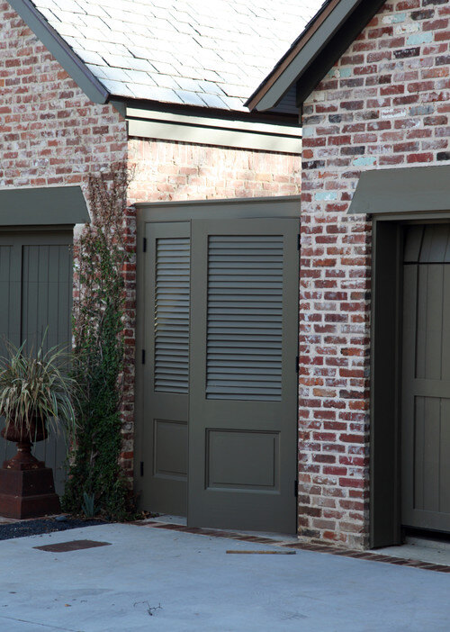 A brick house with black shutters and black garage doors.