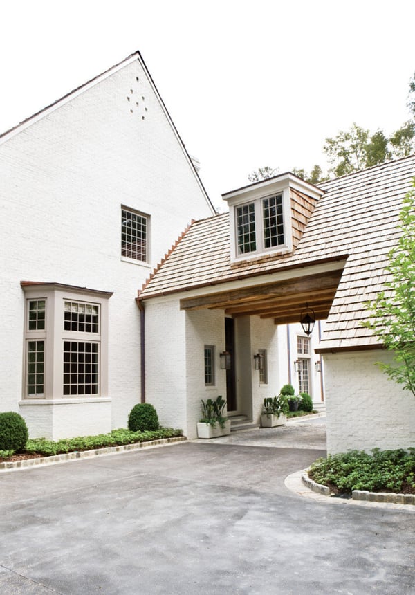 A traditional white brick home featuring a porte cochere.