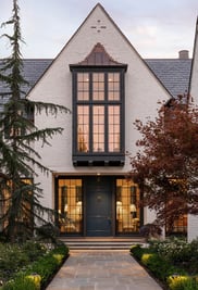 A modern brick house with a gabled roof, luxurious gridded window, and a navy blue front door.