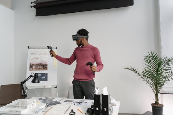 A man in a architecture office looking at a VR house design through a VR headset