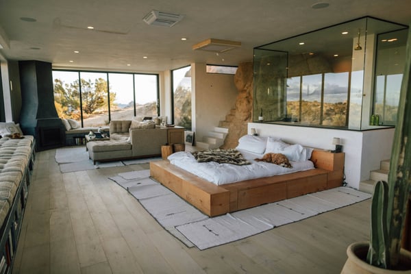 Interior studio bedroom and living room combo of a desert style home with large glass windows looking out to a desert landscape
