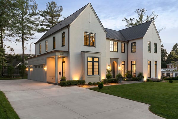 A transitional stucco home with a side garage door and long driveway.
